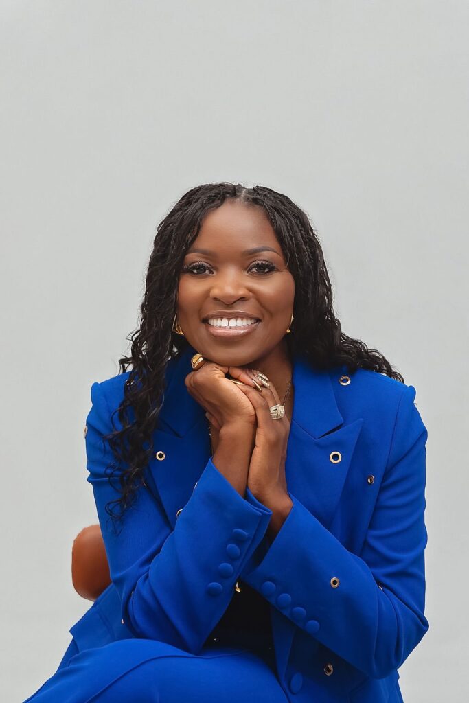 black American woman putting on a blue suit smile at the camera on gray studio background